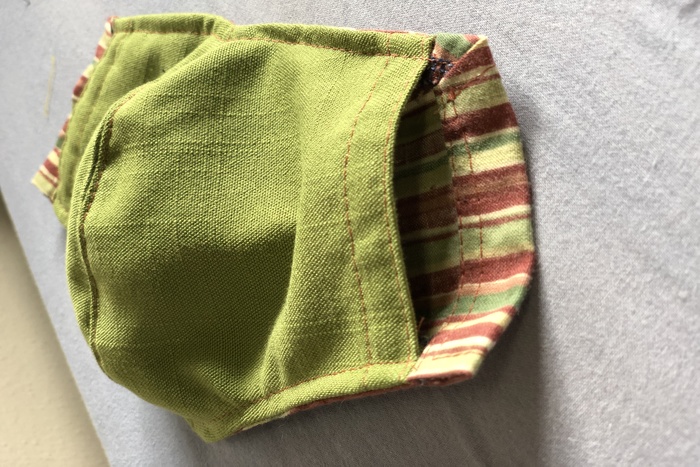 Green cloth pocket with red stripes and red stitching.