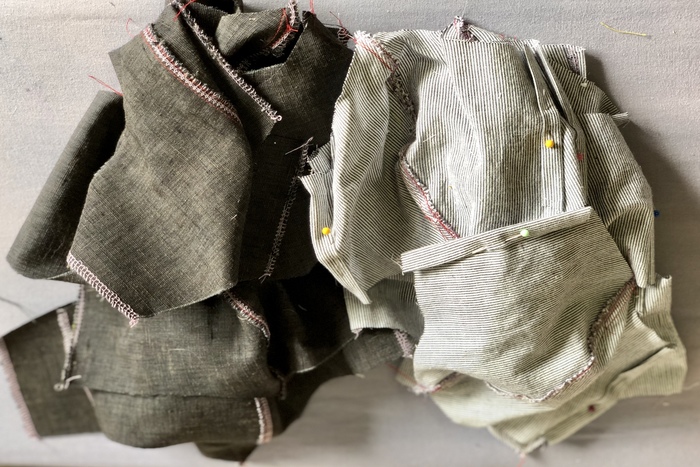 Black and white cloth masks with sewing pins and stitching.