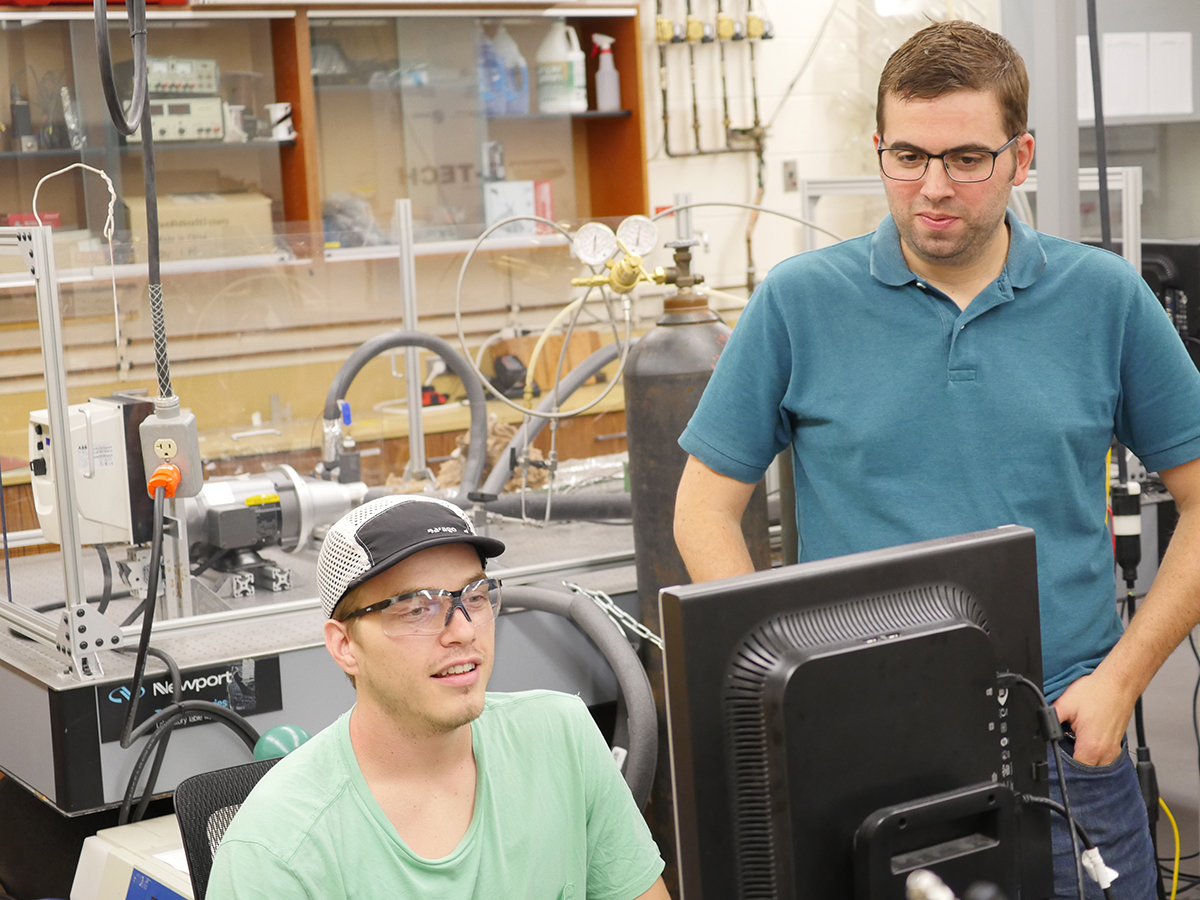 Ethan Matty and Brian Fronk working on a desktop computer in a lab.