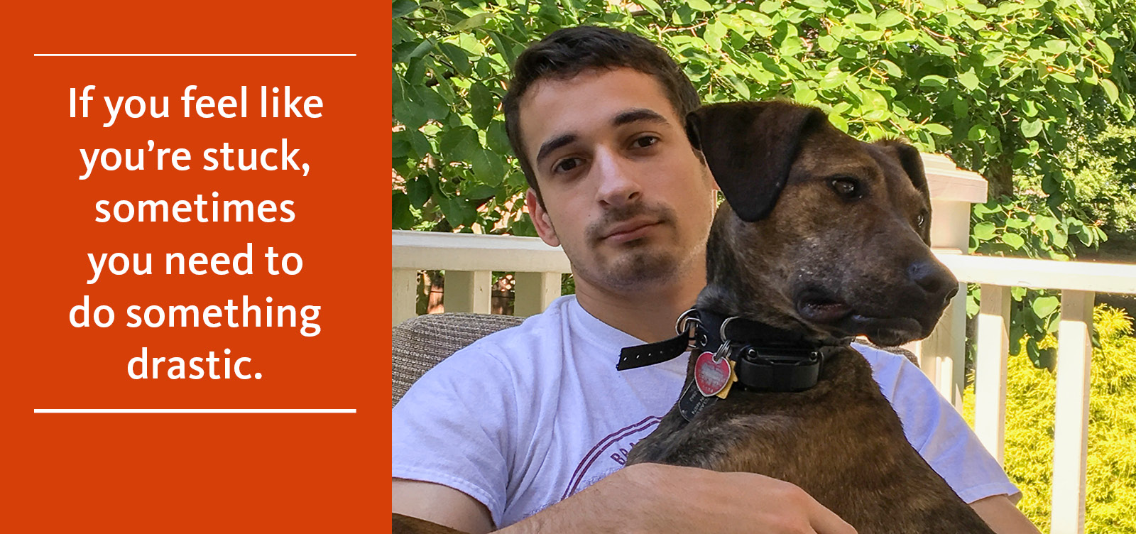 John Lambert holds a brown dog while sitting outside with green foliage in the background.