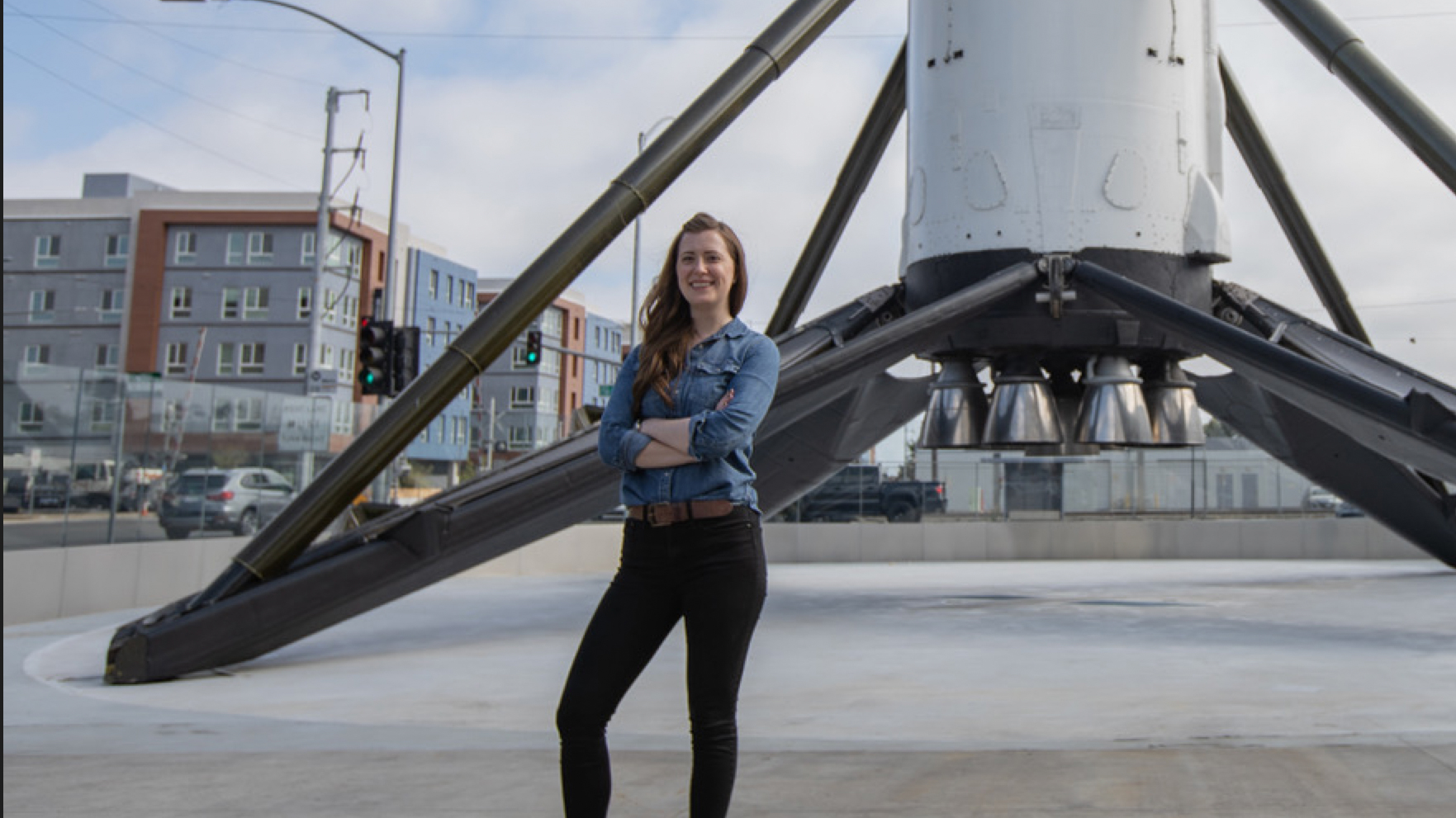 Jill Lewis posing with a rocket in the background.