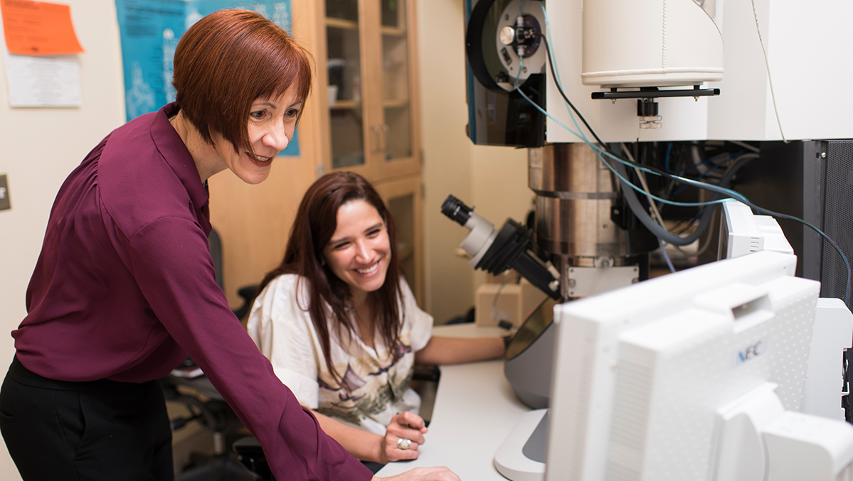 Melissa Santala and Ari Clauser working at a desk with microscopes.
