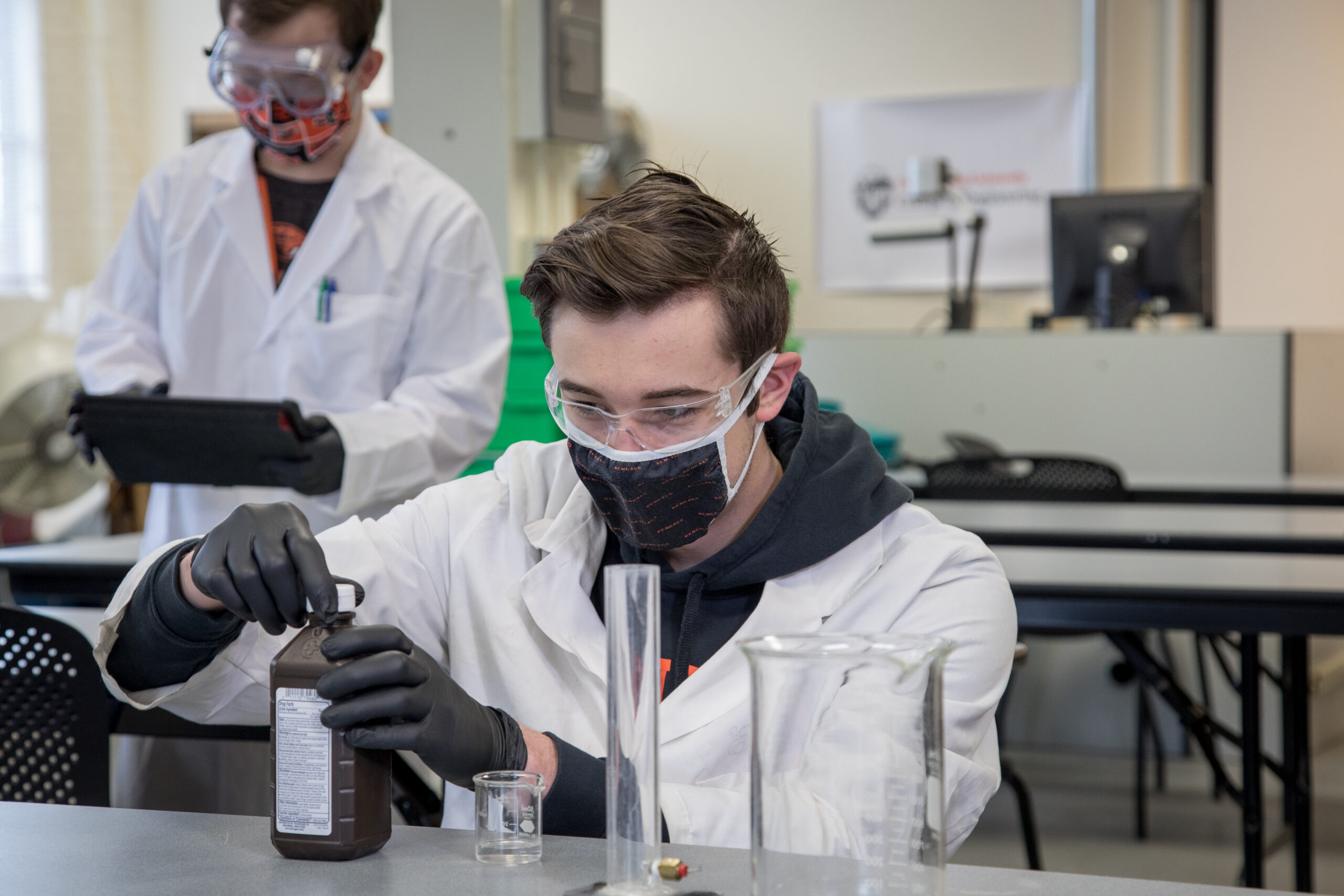 Engineering student wearing protective lab gear working with chemicals.