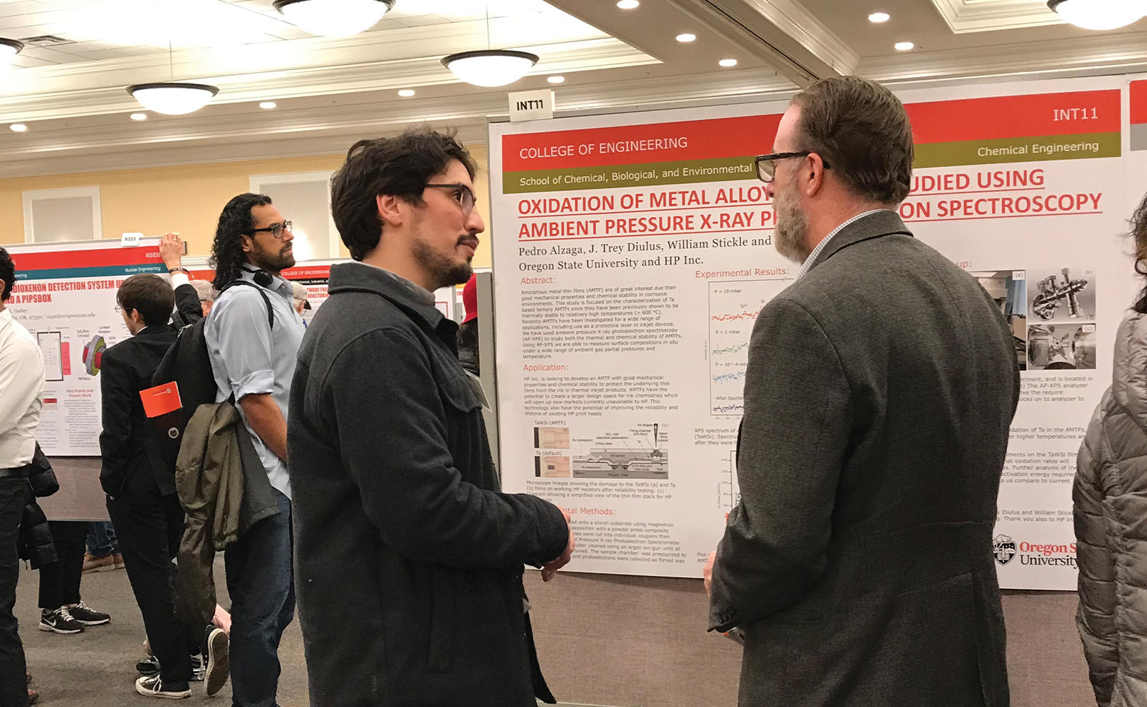 Two engineers discussing a research poster at a project expo. 