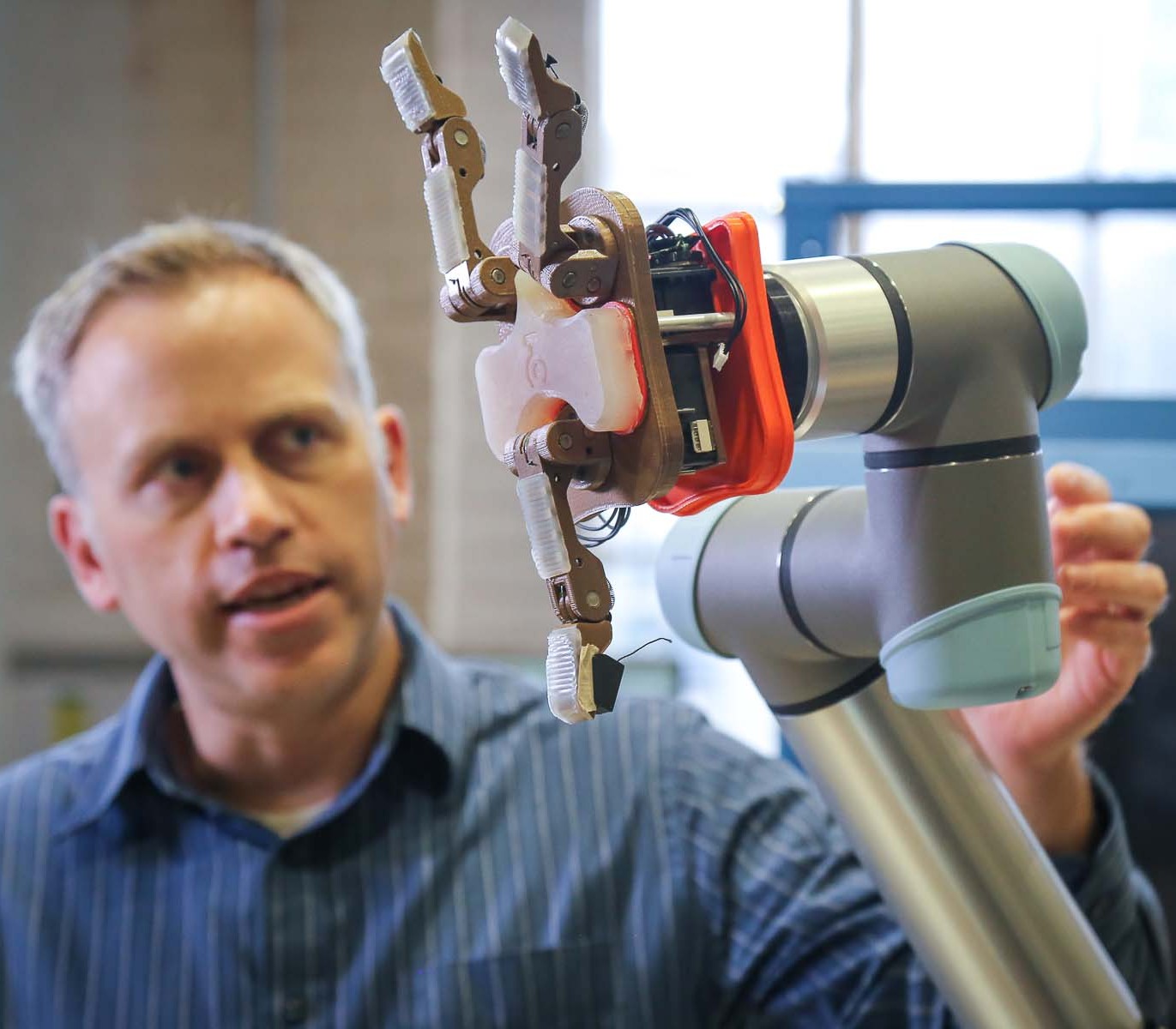 A reseracher showing a robot hand.