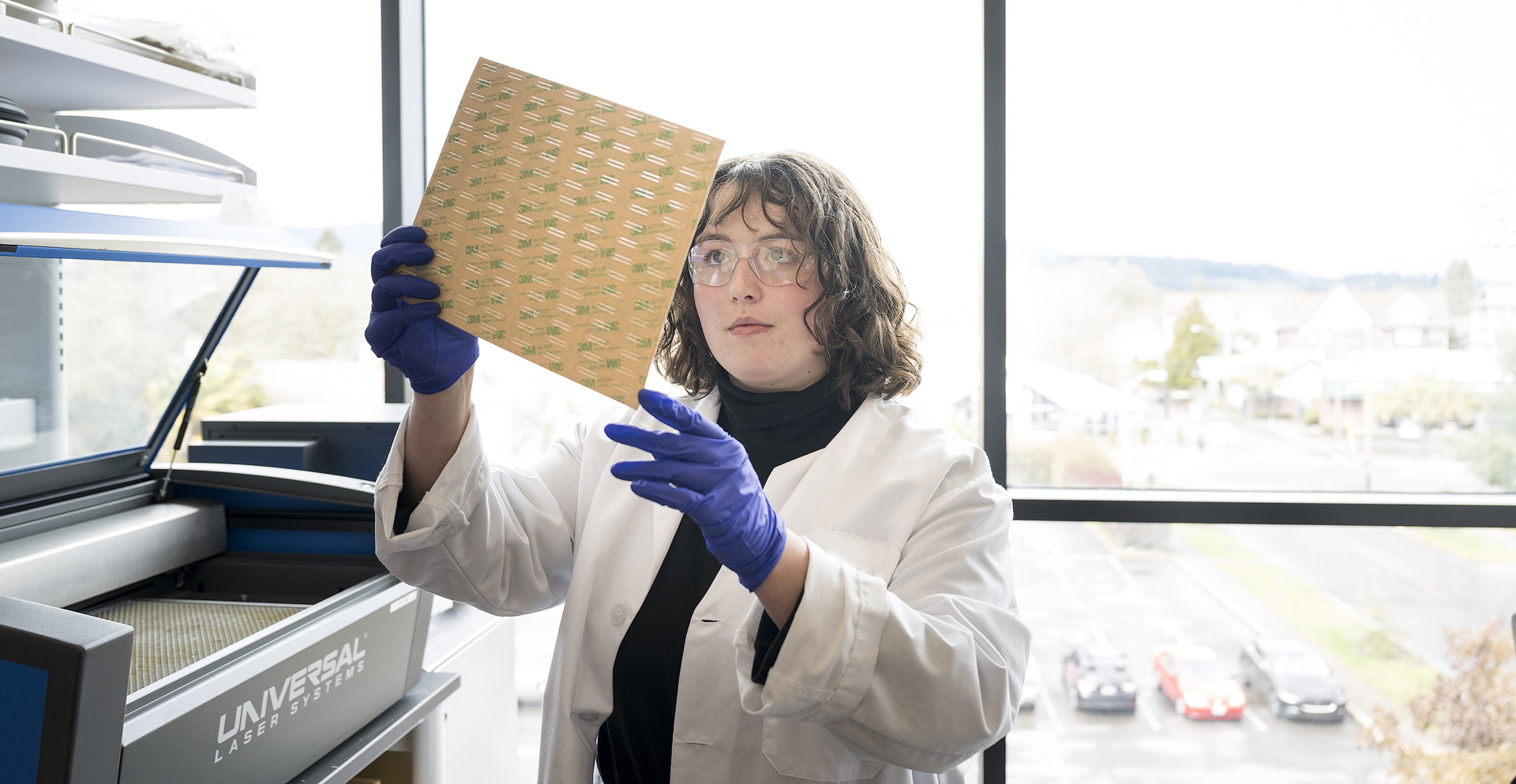 A bioengineering student working with a laser material processing system in the lab.