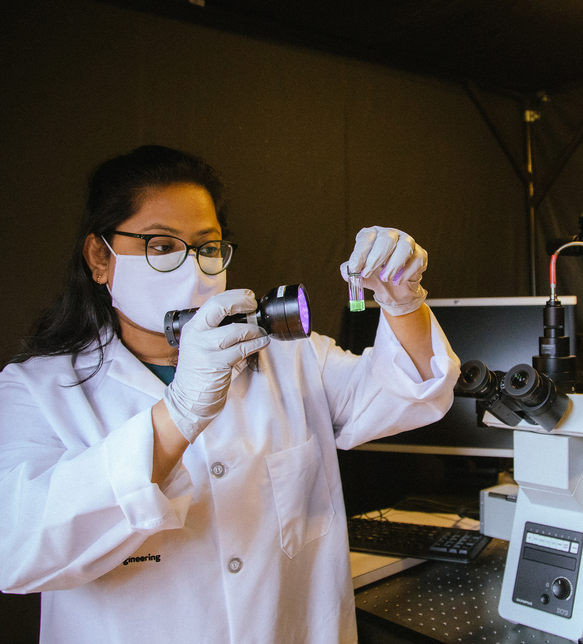 Electrical and computer engineering alumni Sanjida Yeasmin examining a vial of liquid in the laboratory.