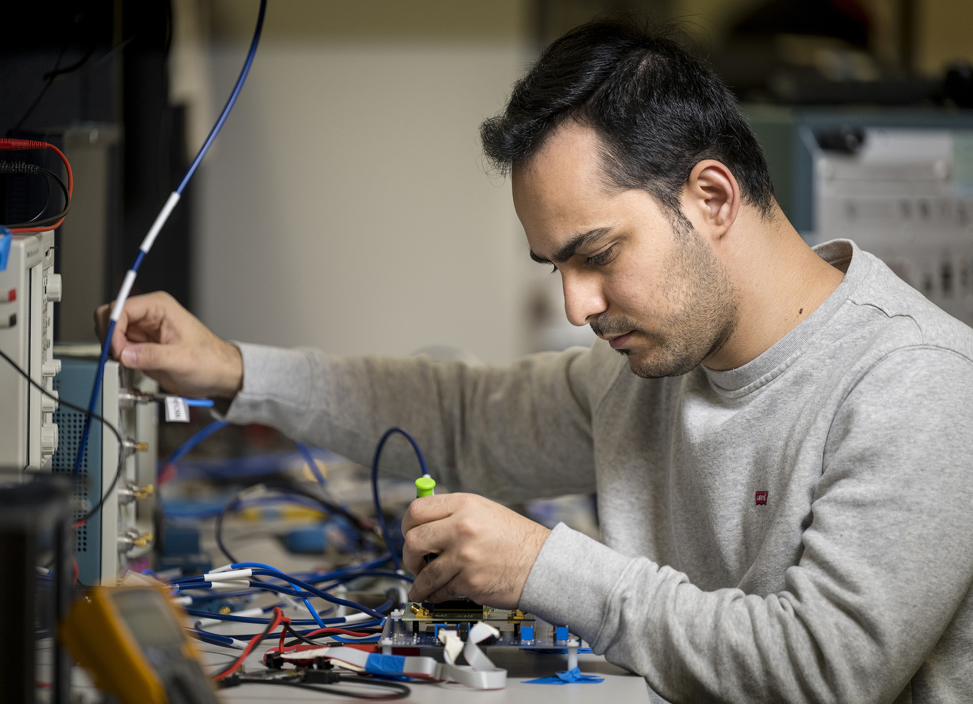 An electrical and computer engineering graduate student working on a circuit board.