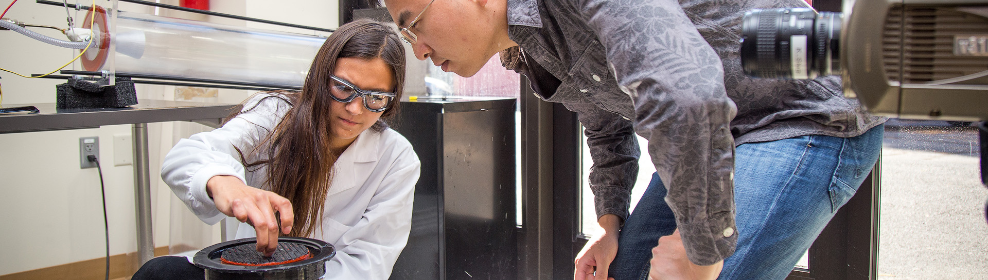 Two students examining a scientific device.