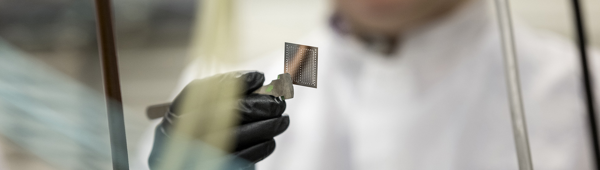 A researcher holding up a computer chip for examination.