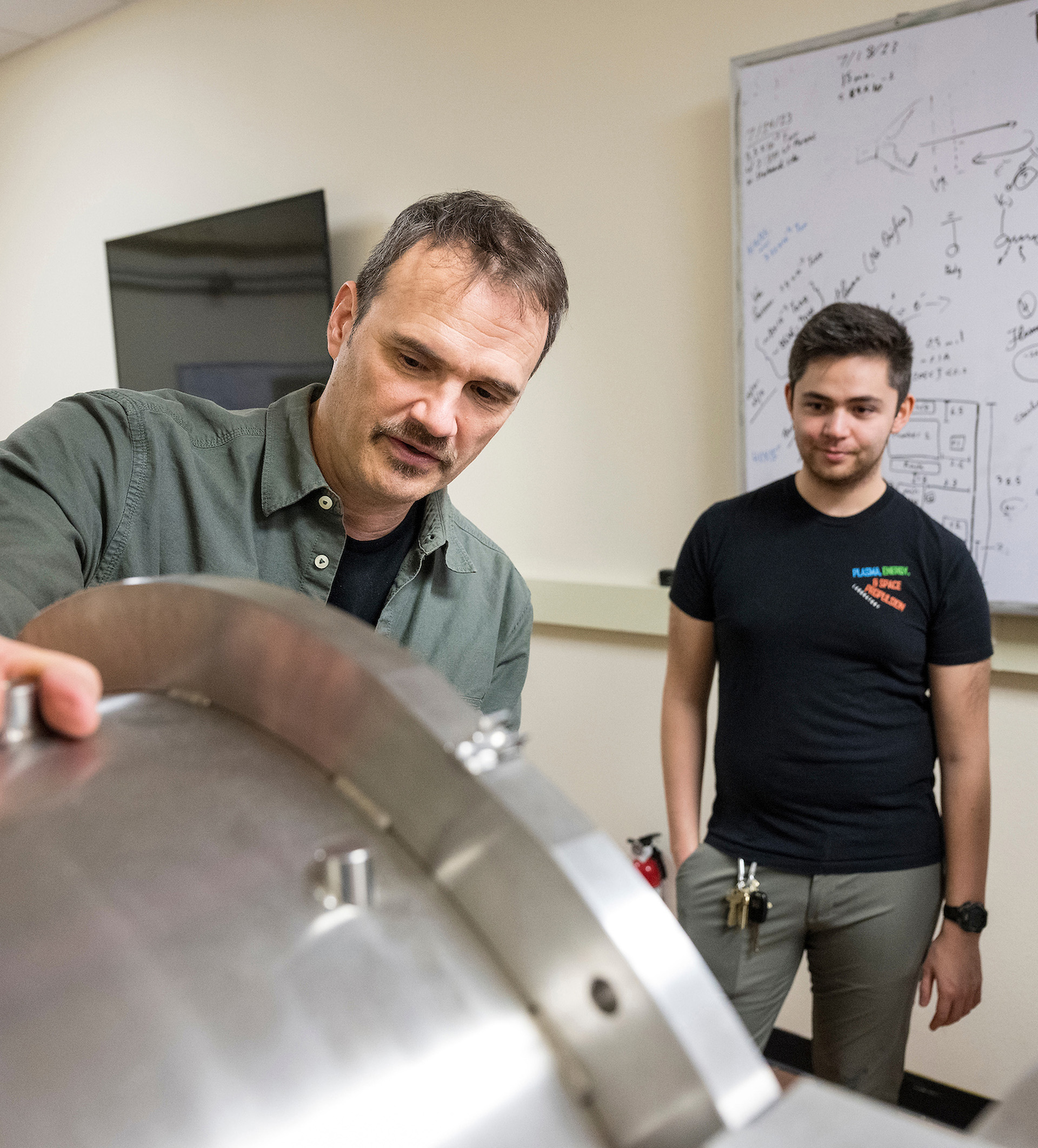 Mechanical engineering professor Richard Wirz explaining the purpose of a piece of laboratory equipment to a student.