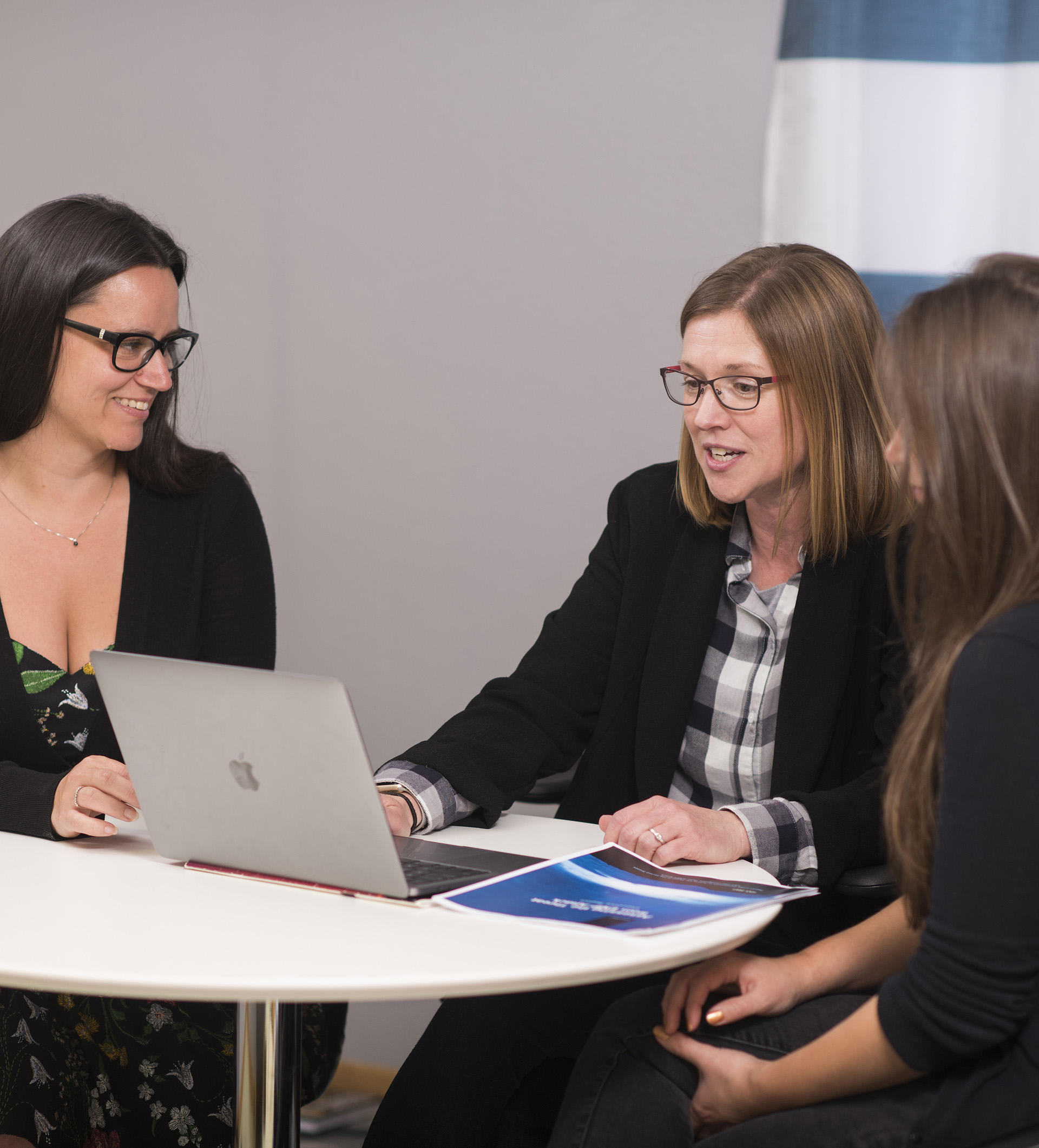 Group of three people gathered around a laptop