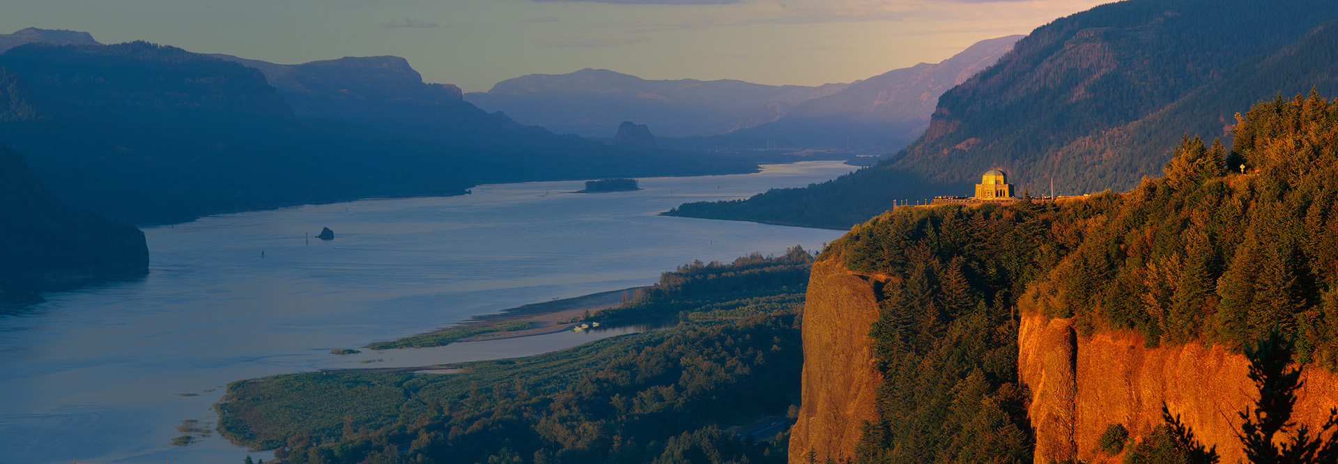 Landscape shot of a cliff with mountains in the background.