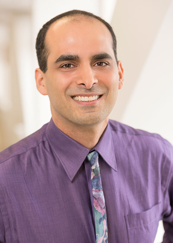 A person in business attire smiles and faces the camera.
