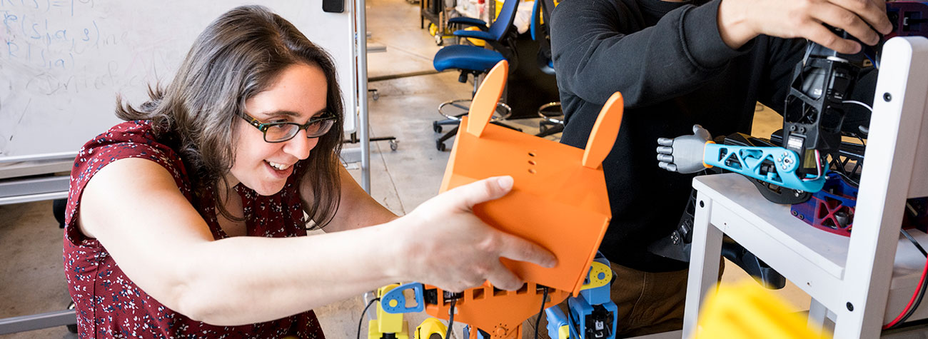 A person holds the head of a colorful robot with rabbit-shaped ears.