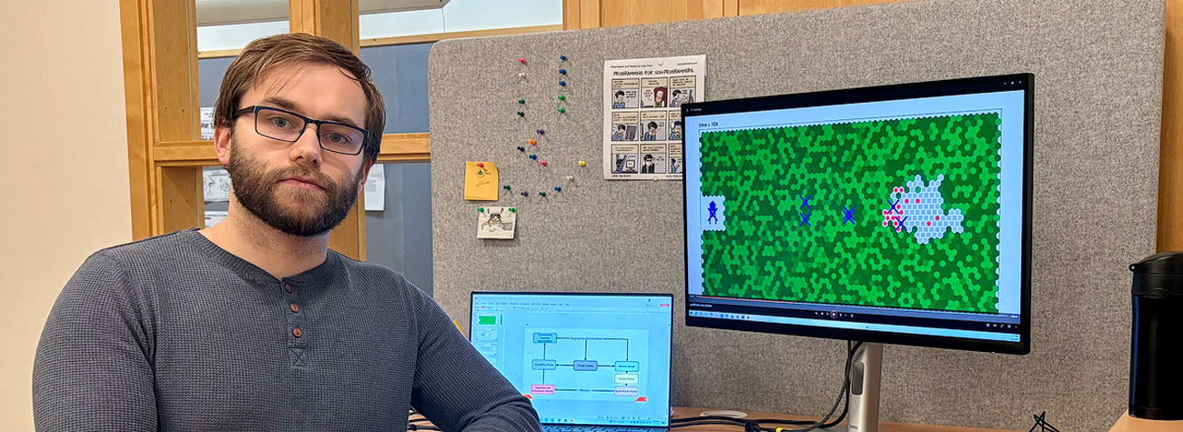Cole Jetton seated at a desk with two monitors