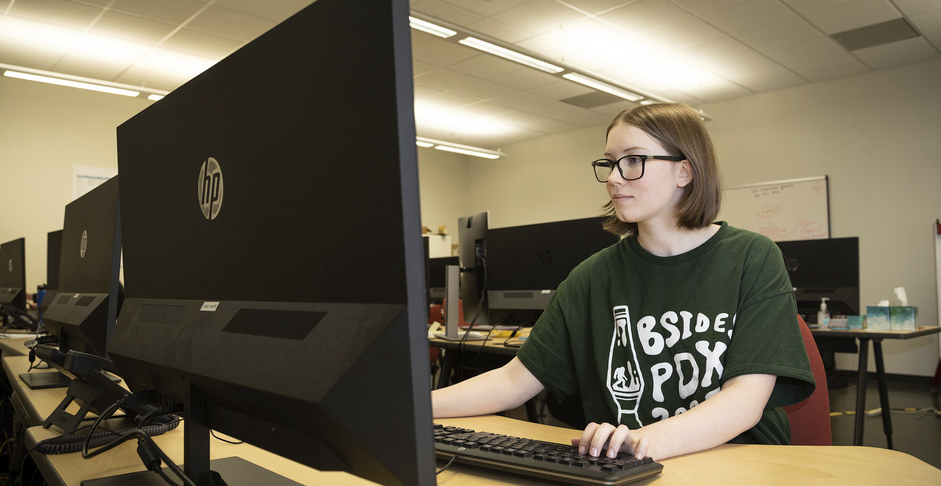 Cybersecurity student typing on a computer in a classroom.