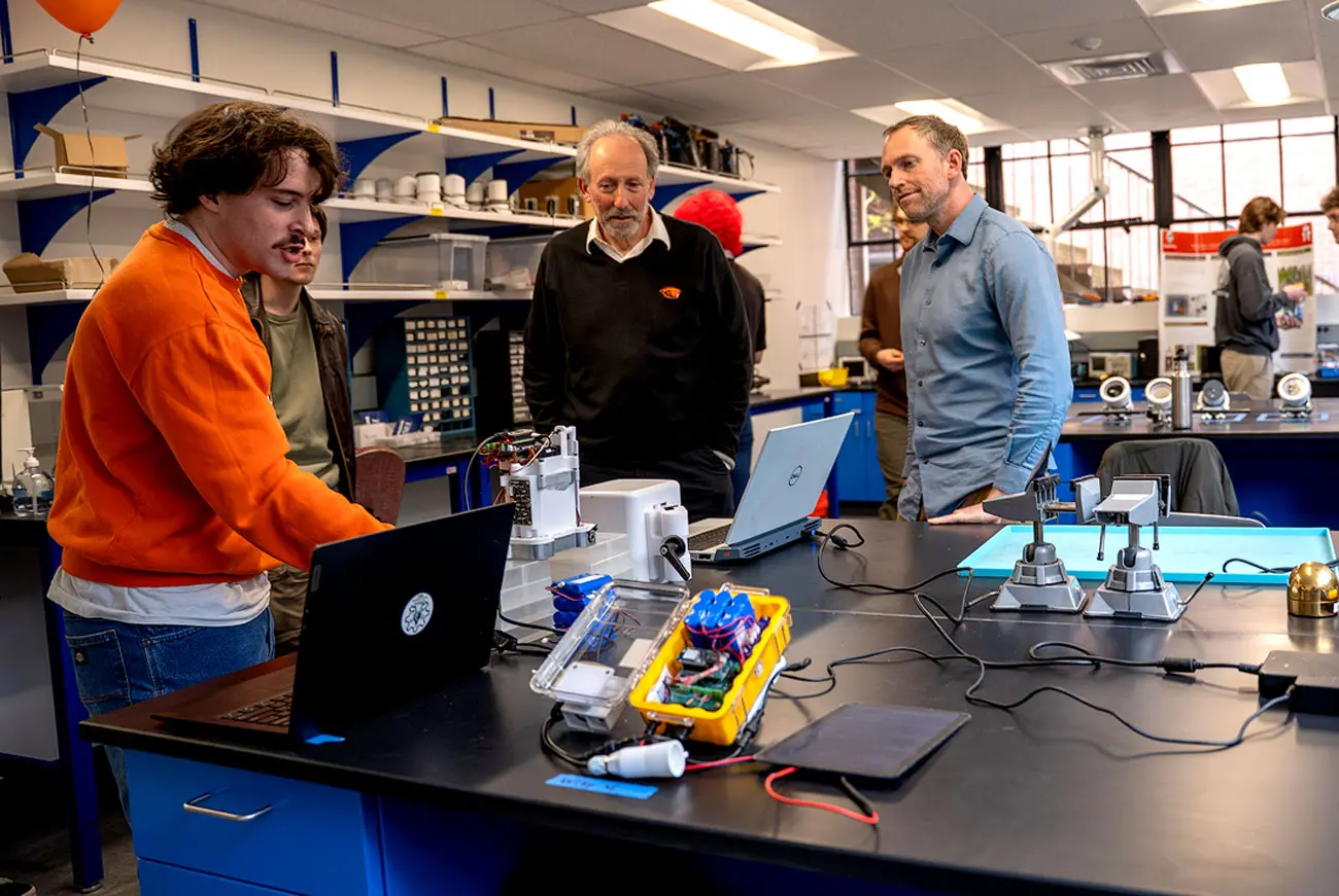 Four people having a conversation in front of various lab equipment.