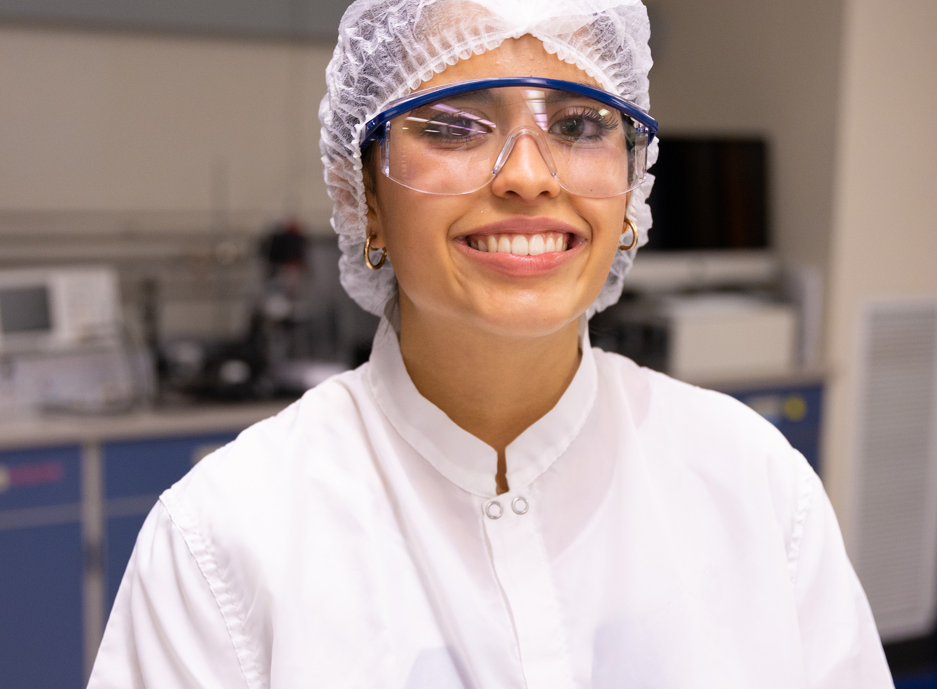 Violet Gualotunia wearing a lab coat and goggles.