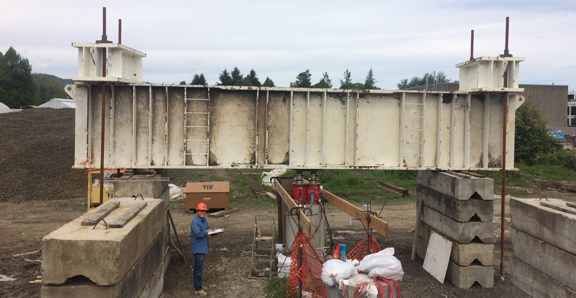A researcher standing below a massive steel beam.