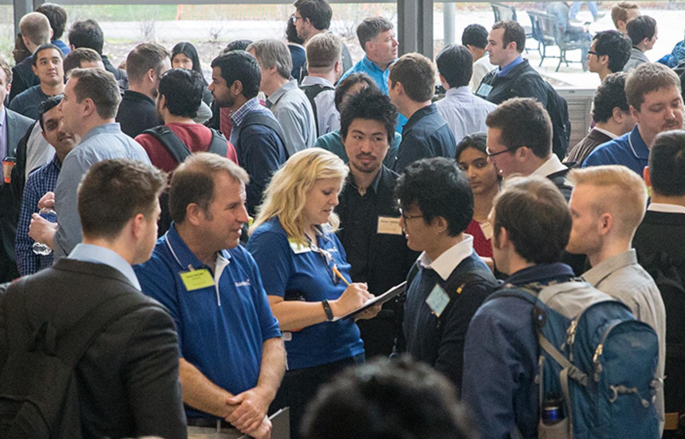 Large crowd of industry representatives and students talking at an EECS industry event.