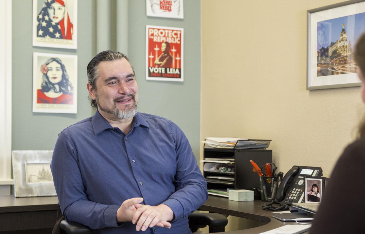 Carlos Jensen in his office, where "We the People" prints hang on the wall behind him.