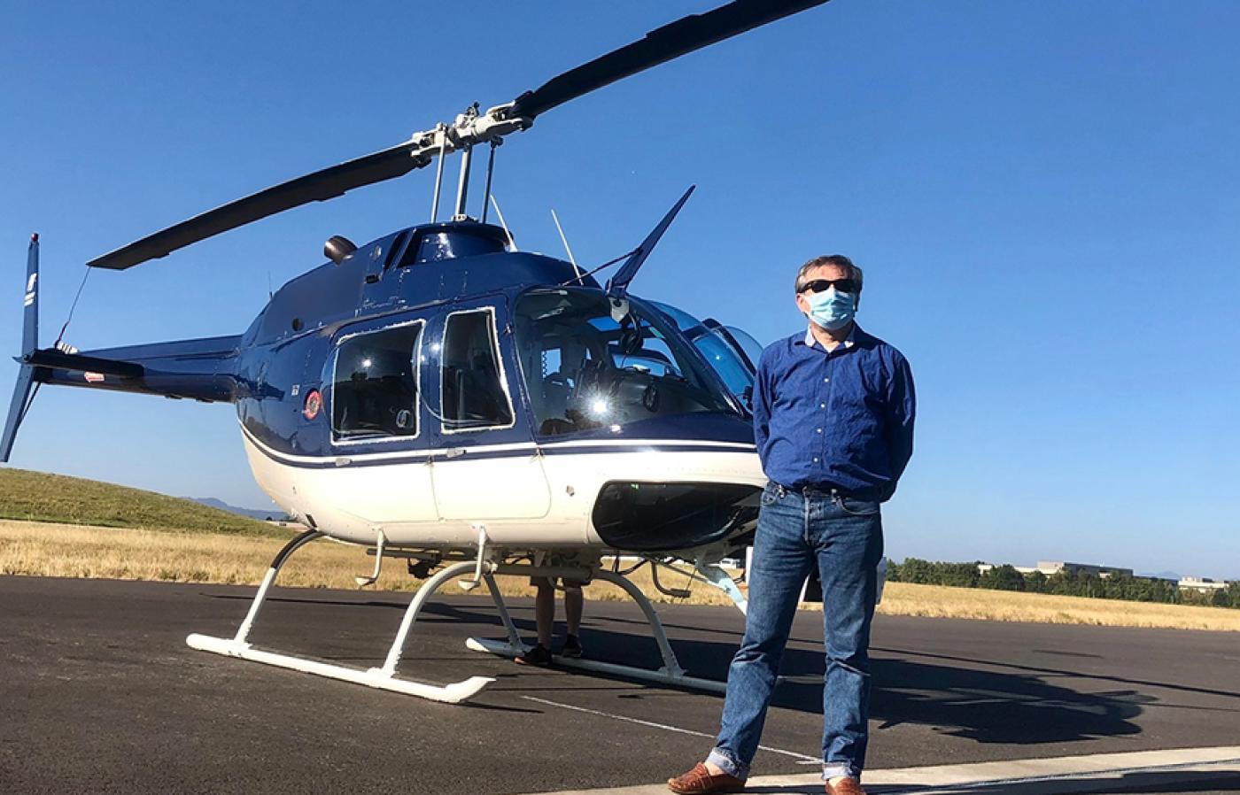 Carlo Tiana standing in front of a helicopter.