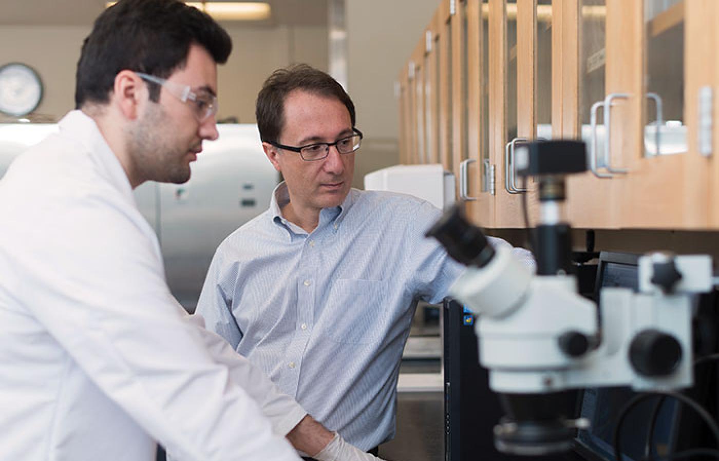 Burkan Isgor and Ali Riza Erbektas examine a sample of concrete in a lab.