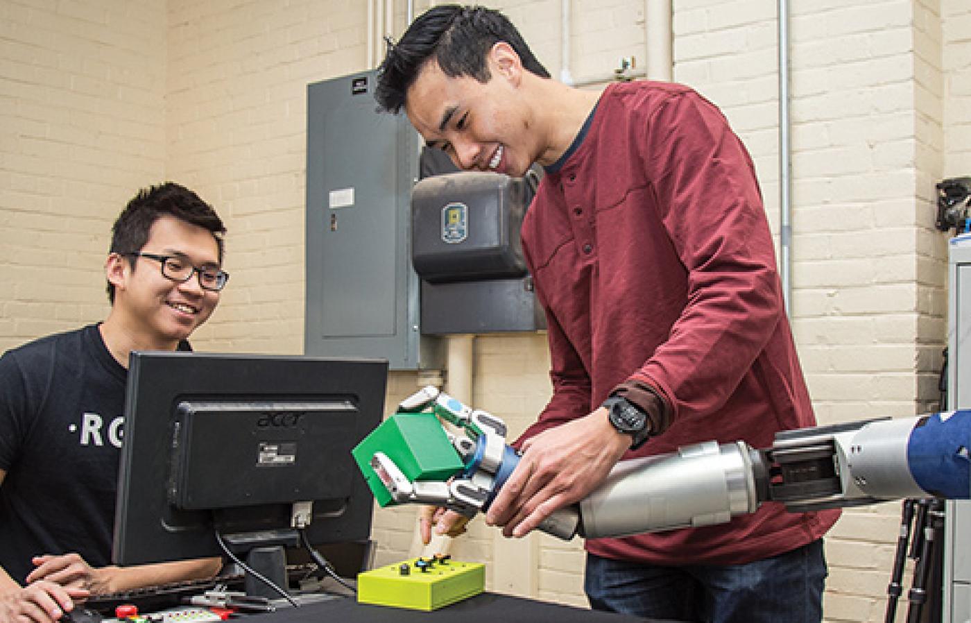 Anthony Le and a colleague interacting with a robotic arm.