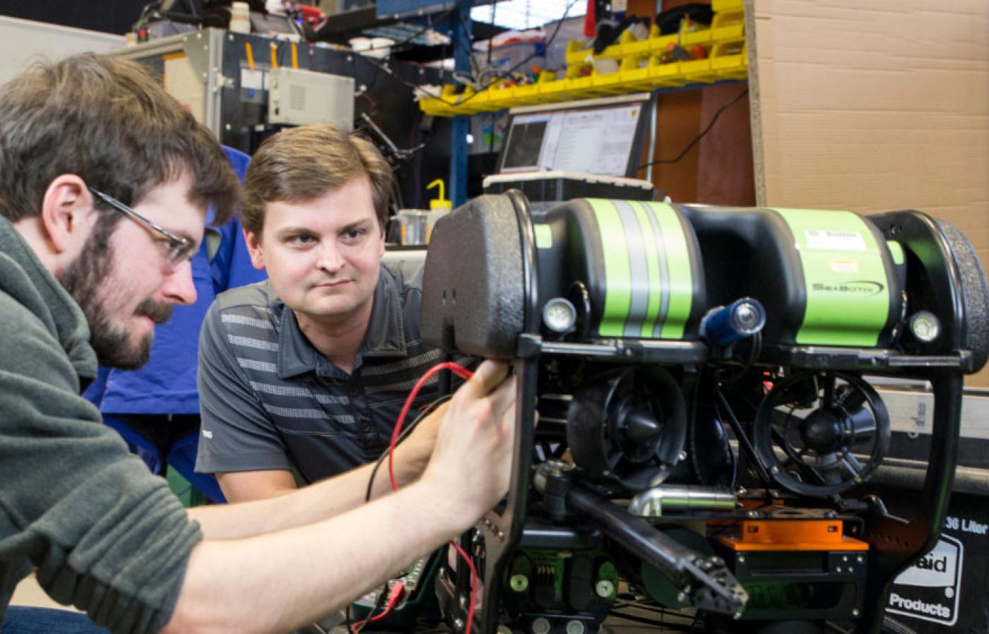 Geoff Hollinger and engineering student working on machine. 
