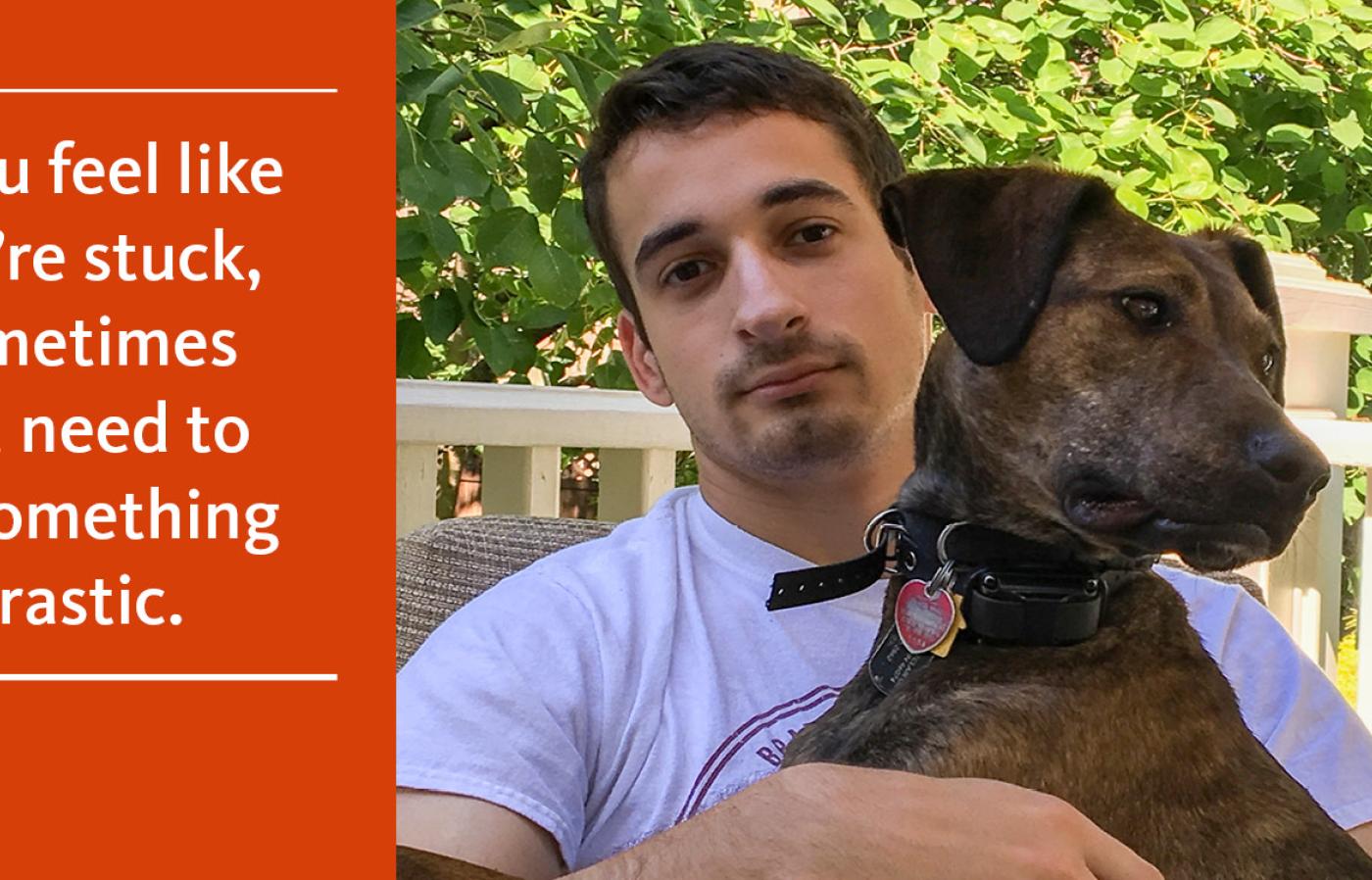 John Lambert holds a brown dog while sitting outside with green foliage in the background.