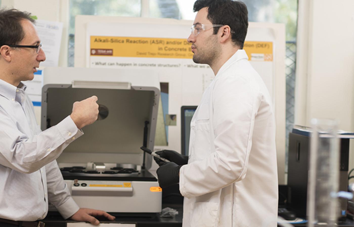Two civil and construction engineering researchers wearing protective gear in a lab.