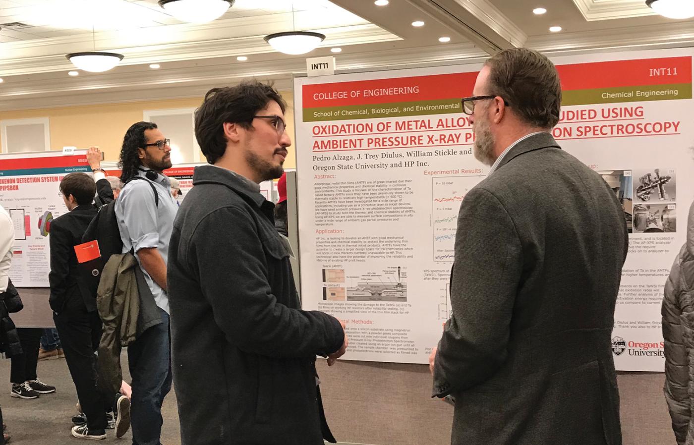 Two engineers discussing a research poster at a project expo. 