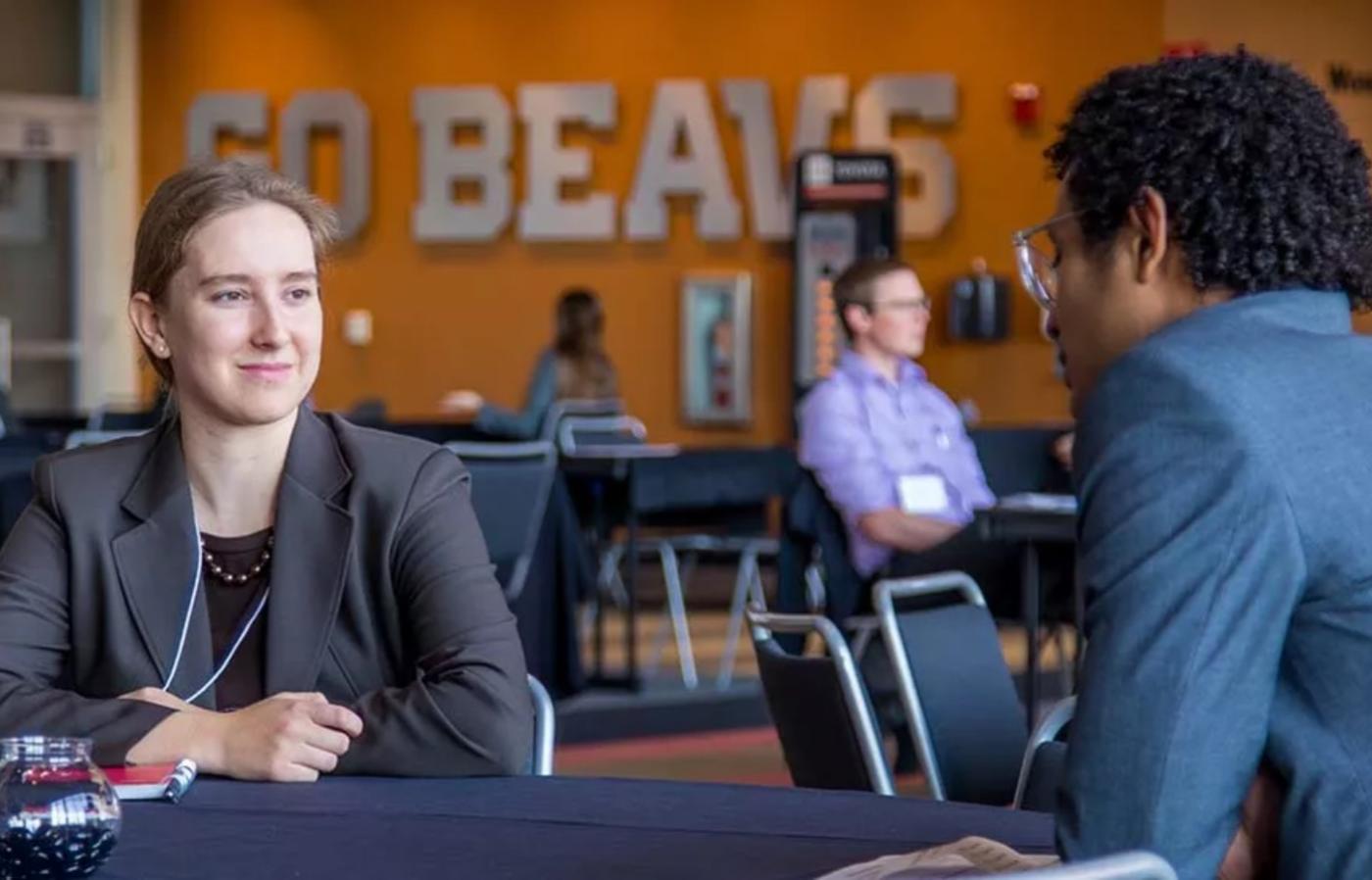 Two people having a conversation sitting at a table.
