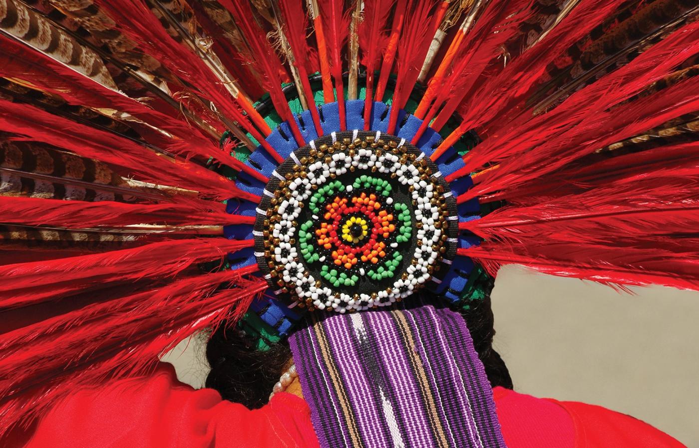 Red feathered headdress with flower patterned, colorful beads.