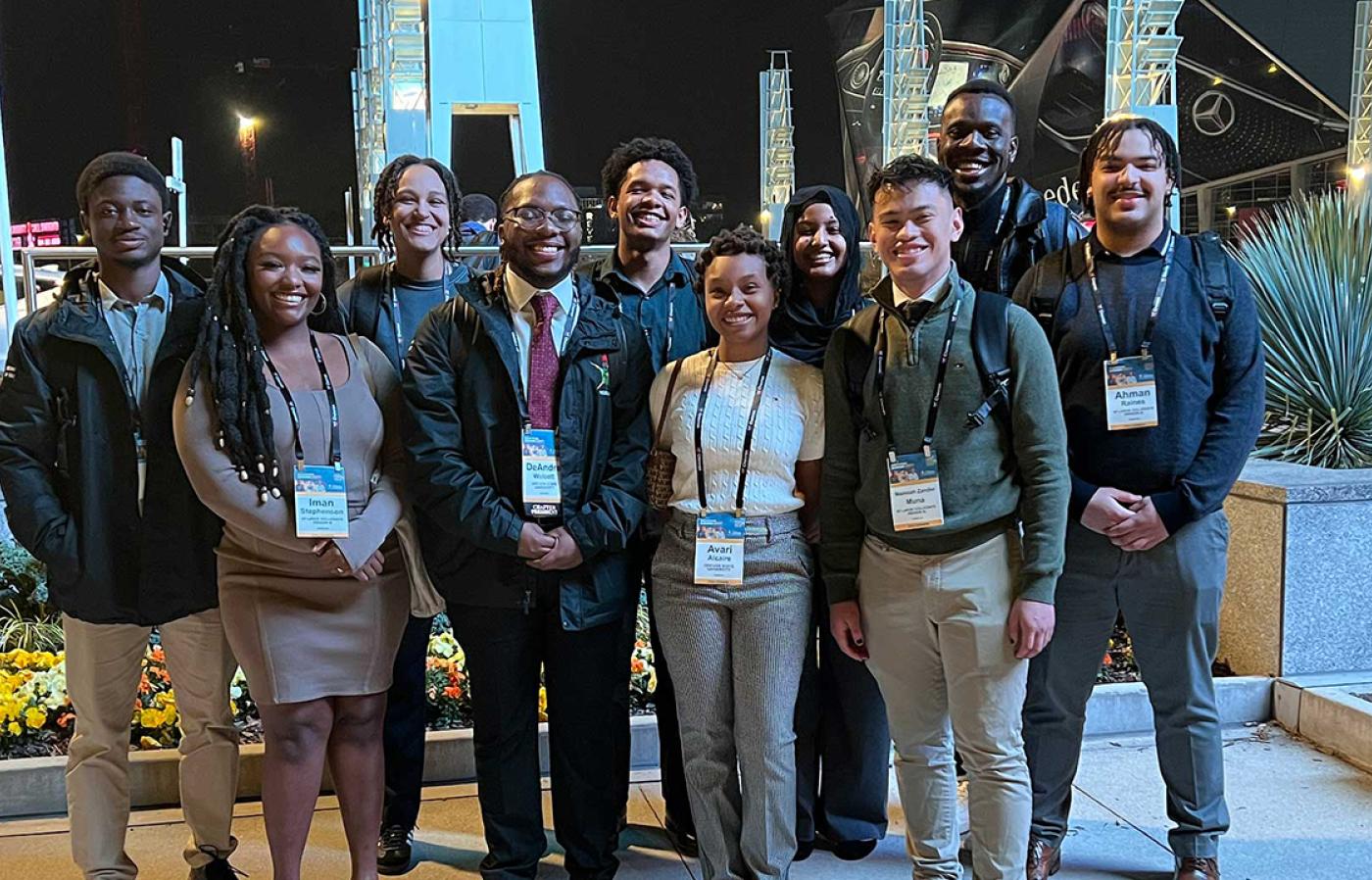 10 students standing shoulder-to-shoulder with each other for a group portrait wearing conference lanyards