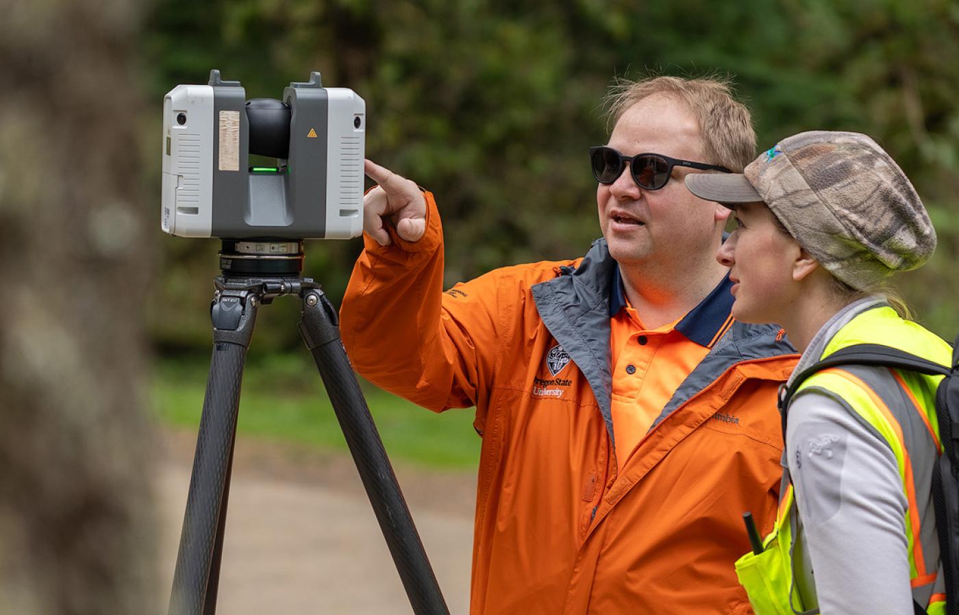 Two researchers look at 3D scanning instrument. 