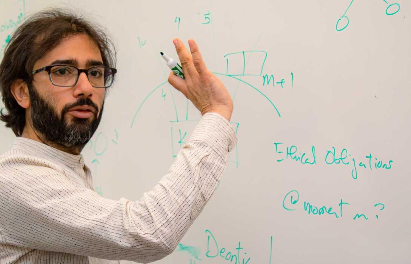 Oregon State Professor Houssam Abbas explaining engineering principles using on a whiteboard