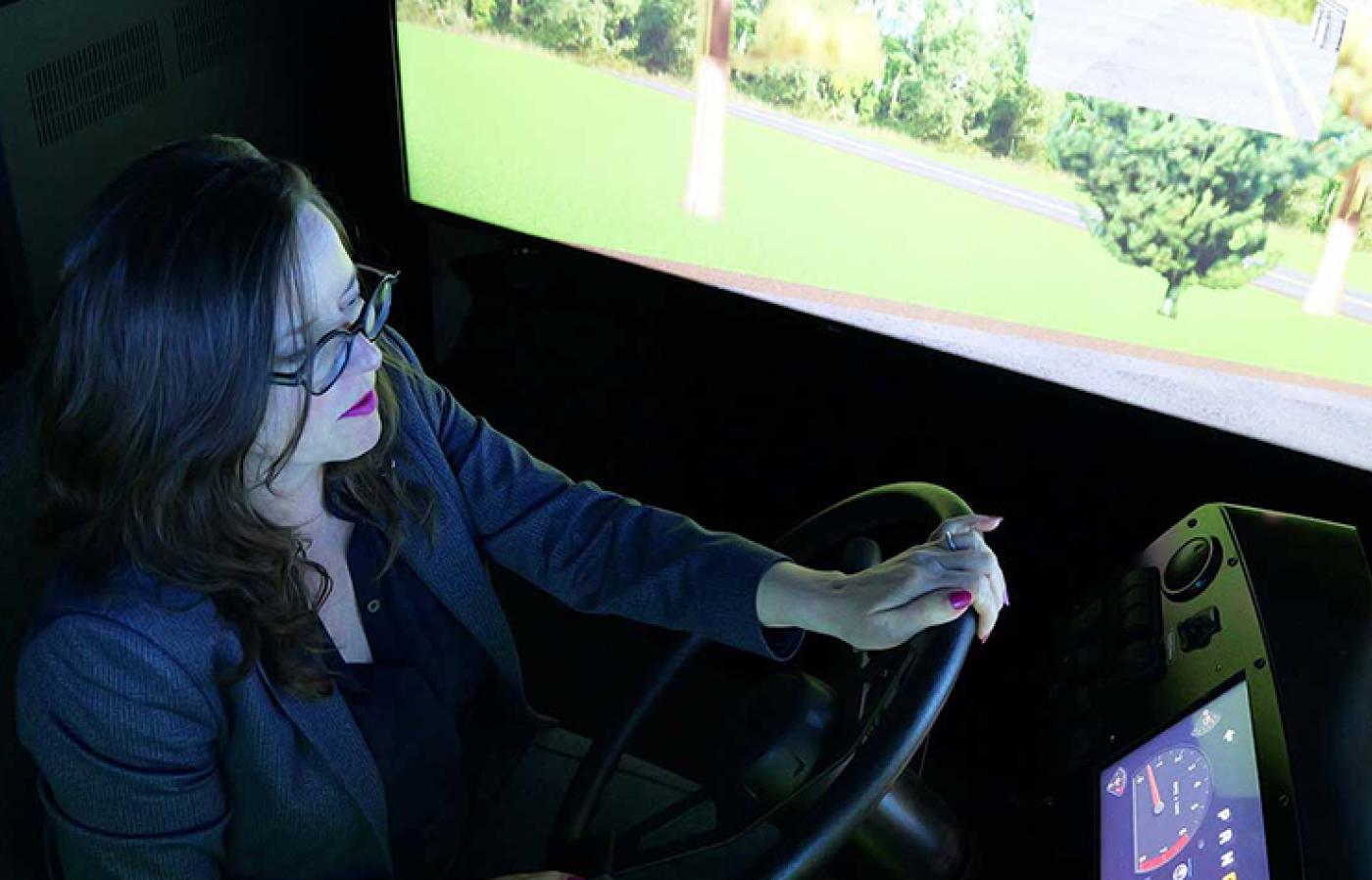 A person sitting in an indoor driving simulator with hands on the steering wheel.