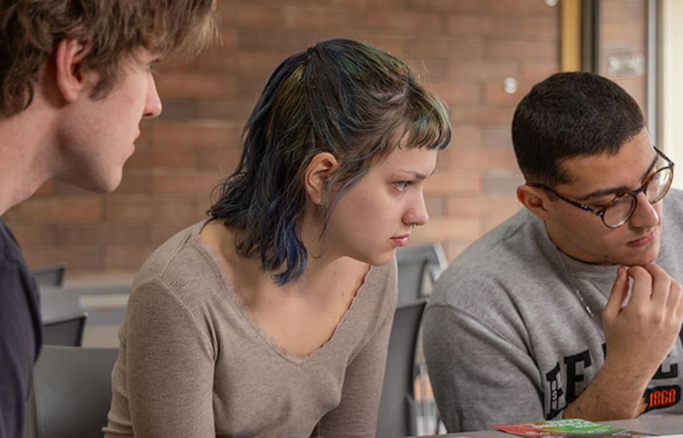Three students looking at a computer screen inquisitively. 