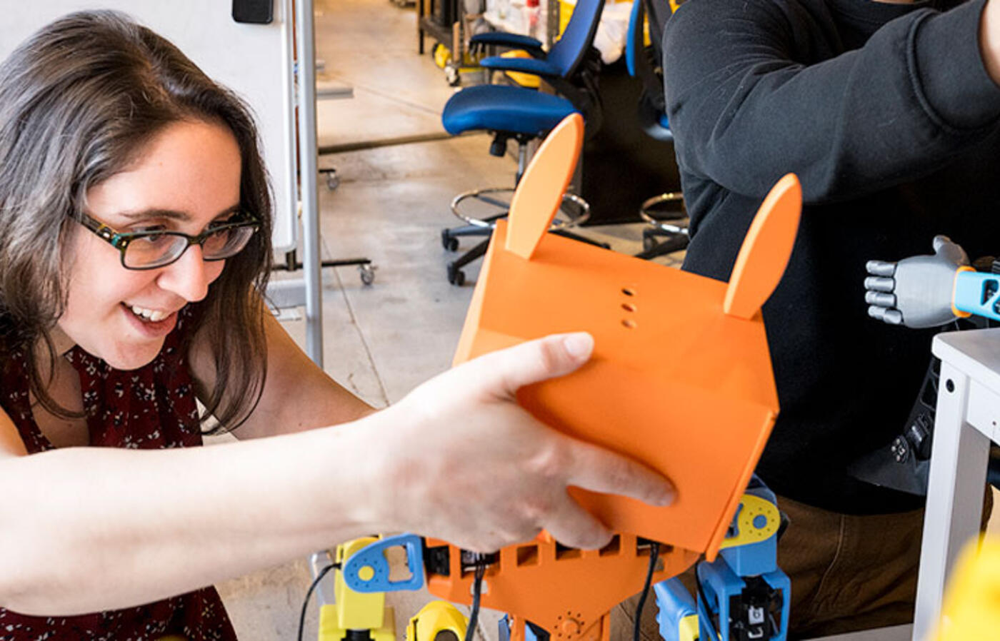 A person holds the head of a colorful robot with rabbit-shaped ears.
