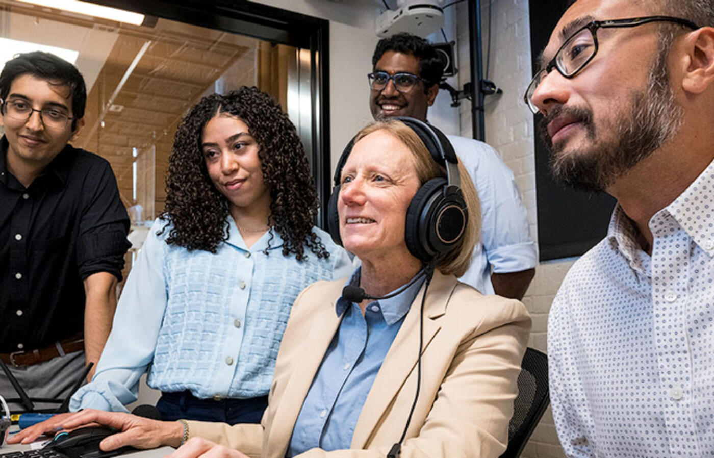 A professor and a group of students looking at a computer screen.