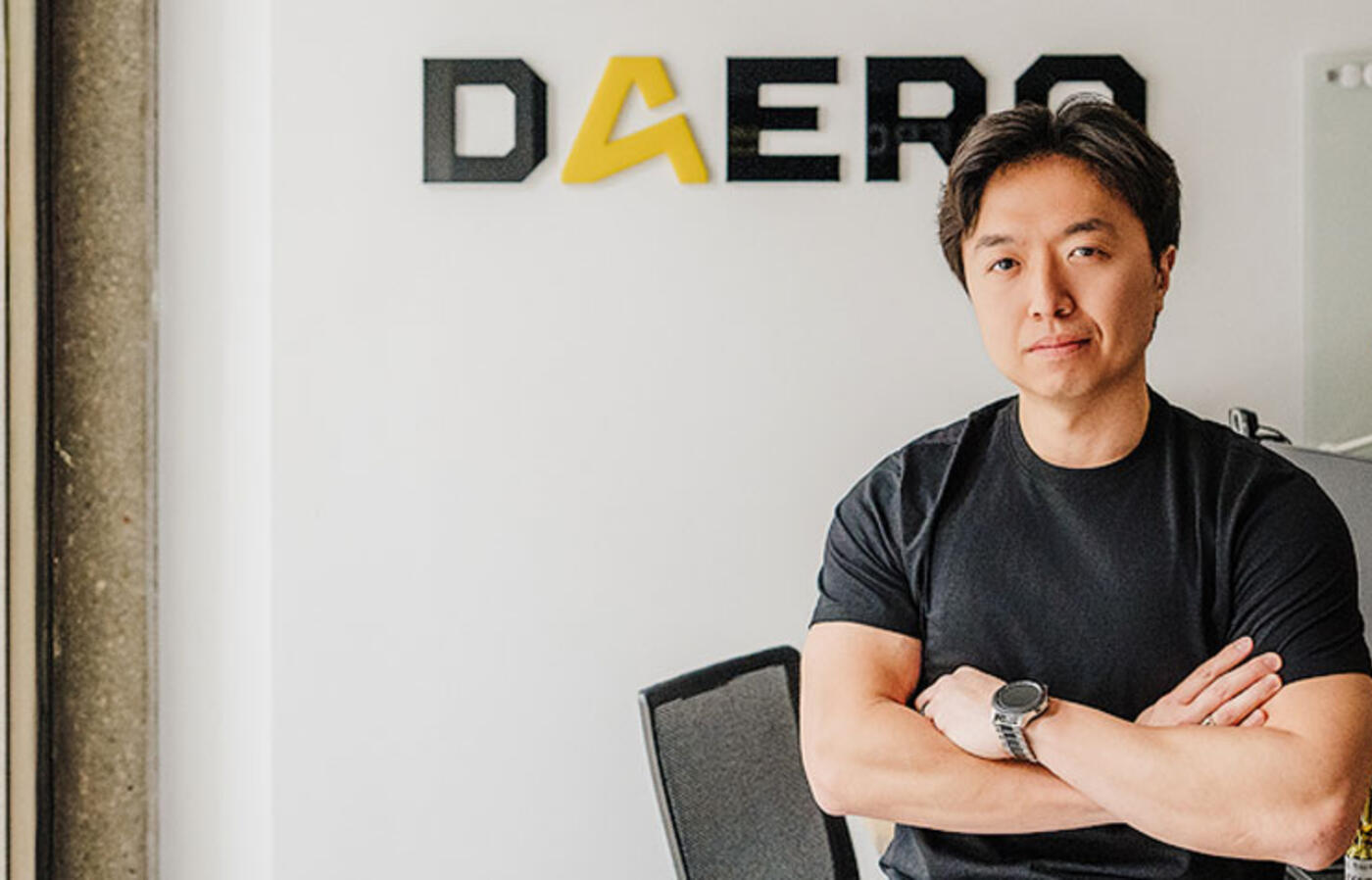 Alex Park posing with arms crossed in front of the DAERO company logo.