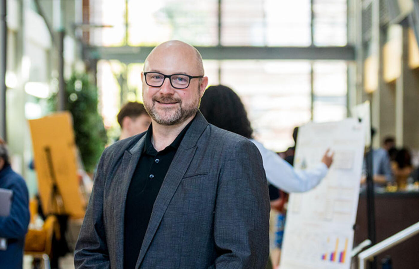 David Zier poses in Kelley Engineering Center atrium with presenters and posters in the background.
