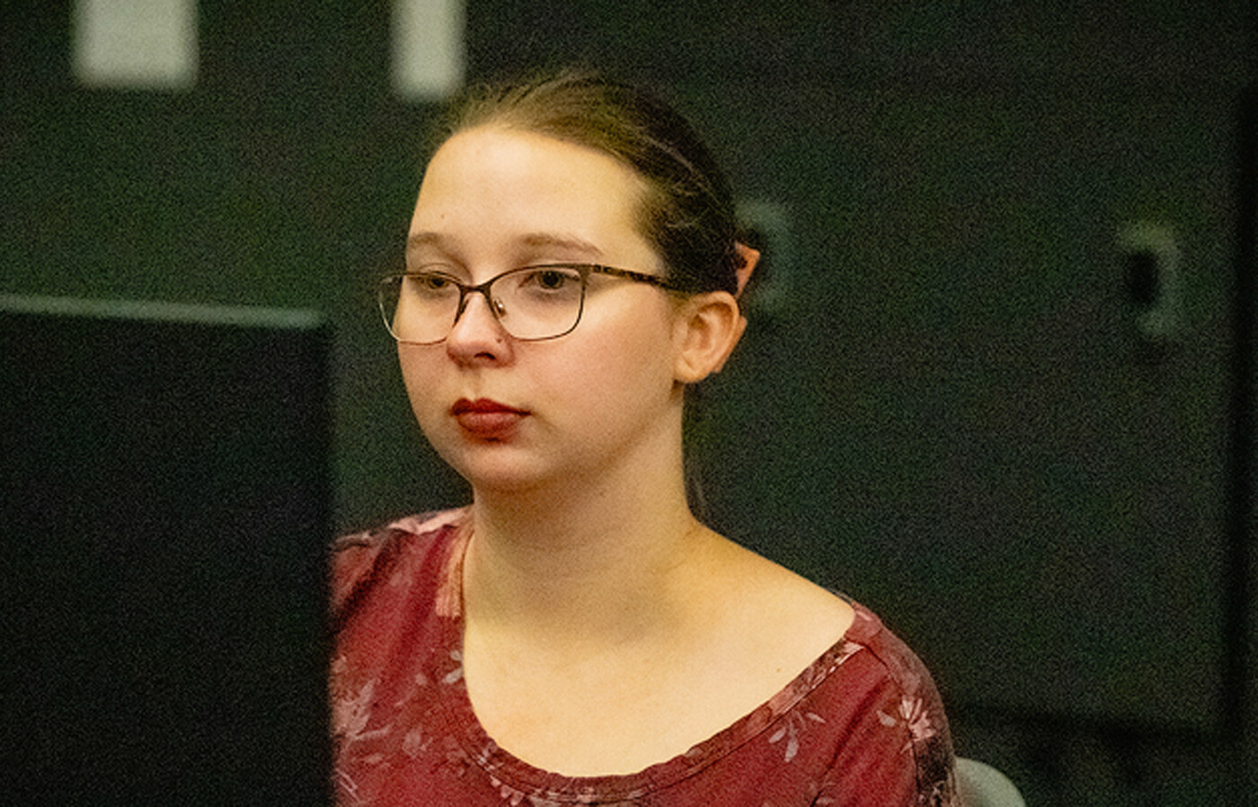 Kyla Daskalos, wearing a red shirt, looks at a computer screen.