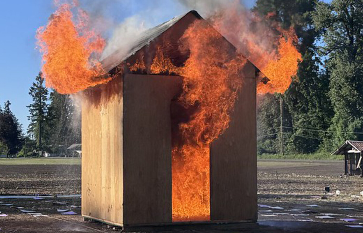 A small wooden hut that is on fire.