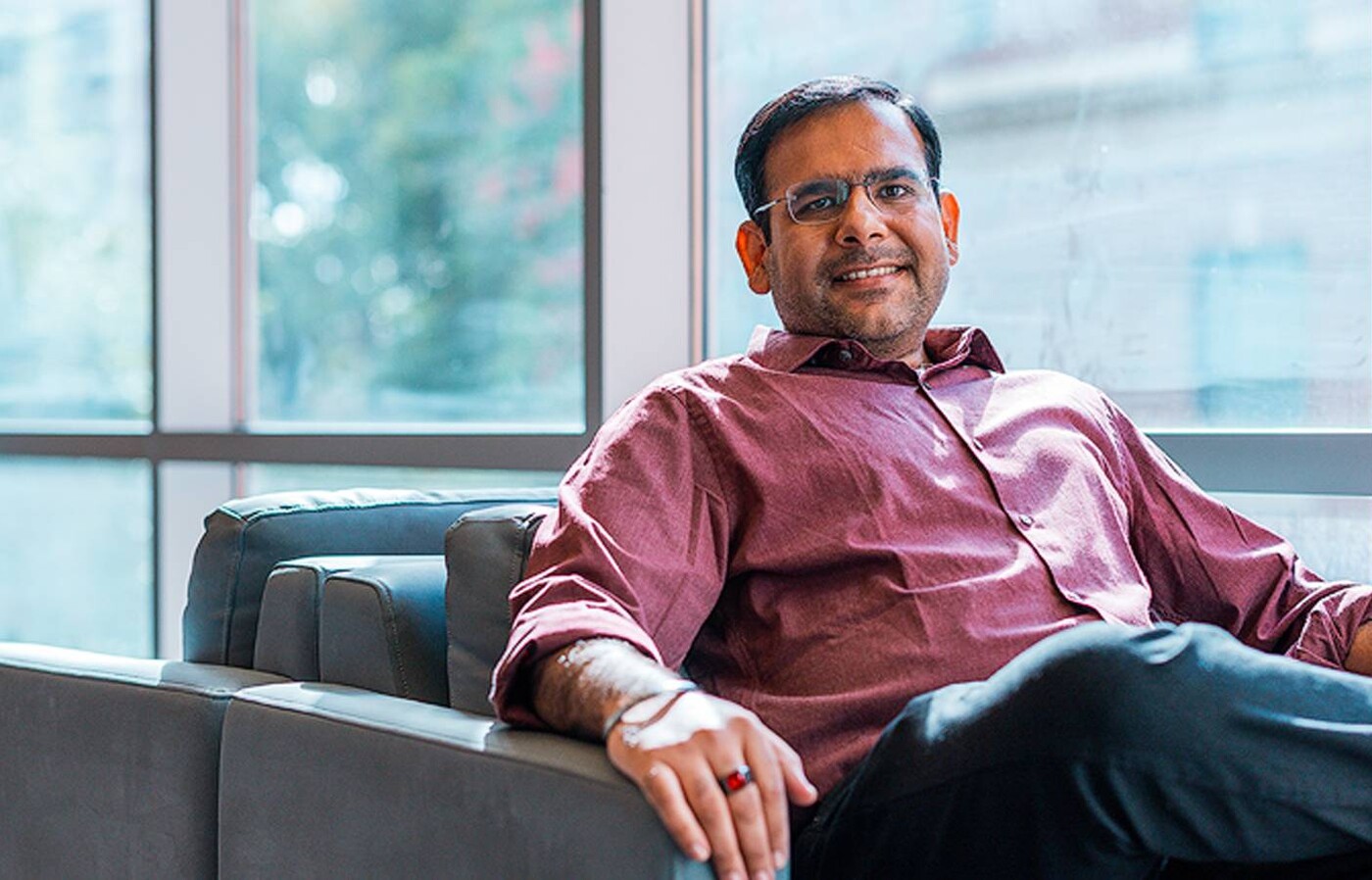 Manish Motwani sits smiling in a chair by the windows of Kelley Engineering.
