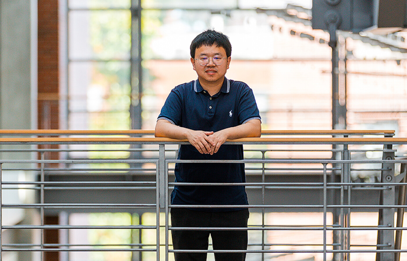 Xin Liang stands inside Kelley Engineering, a modern campus building with large windows in the background.