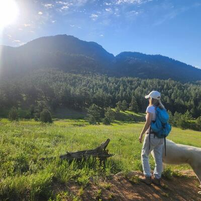 Ami Gates in a meadow hiking with her dog on a sunny day.