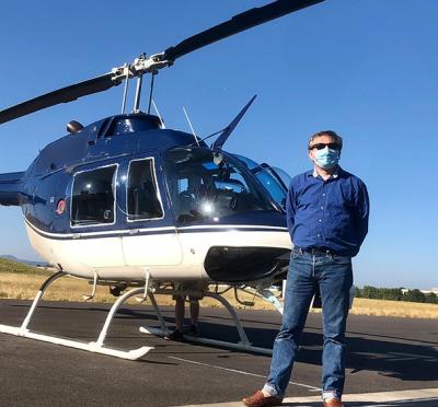 Carlo Tiana standing in front of a helicopter.